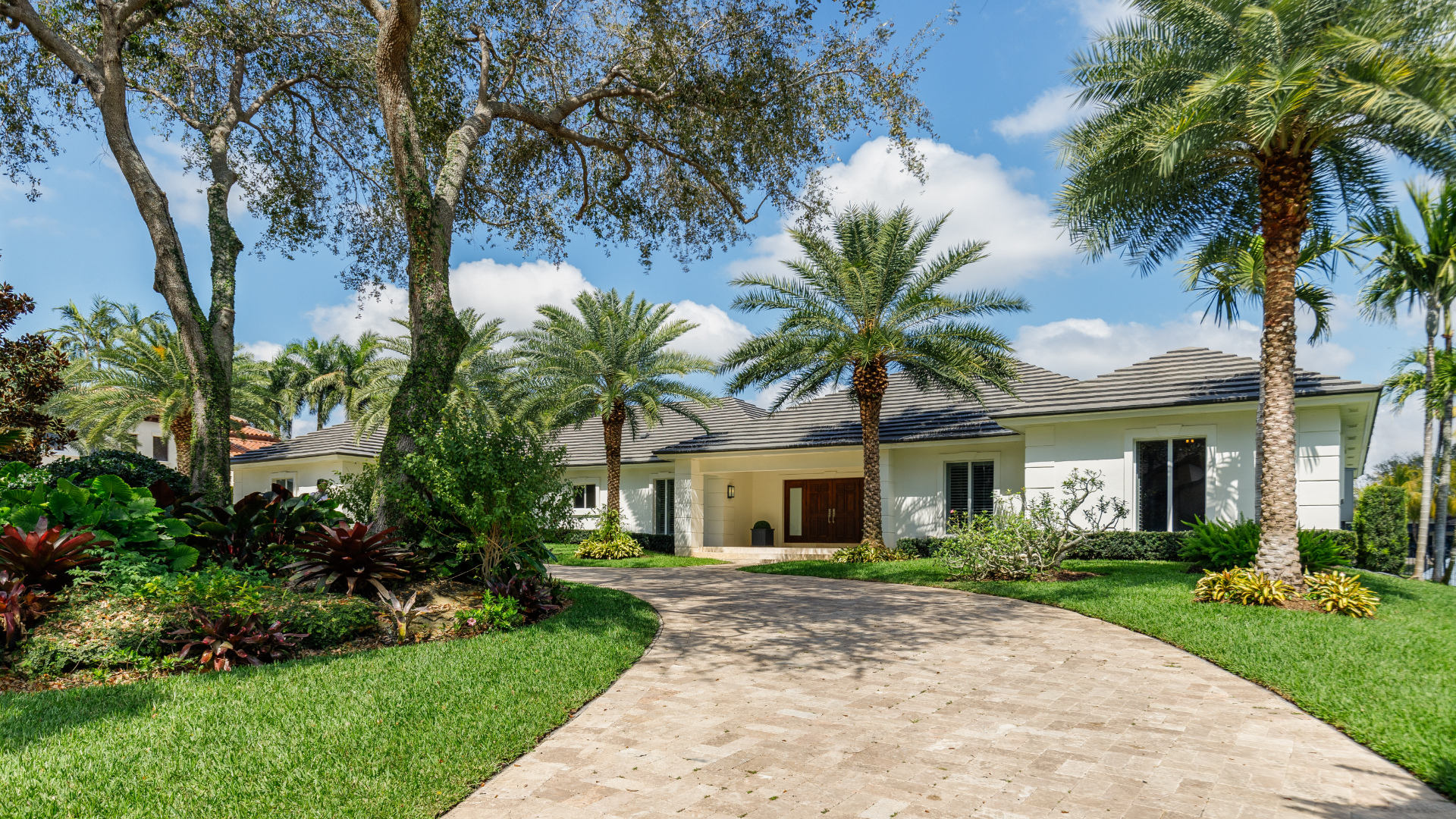 A one story white home surrounded by palm trees in Lithia, FL.